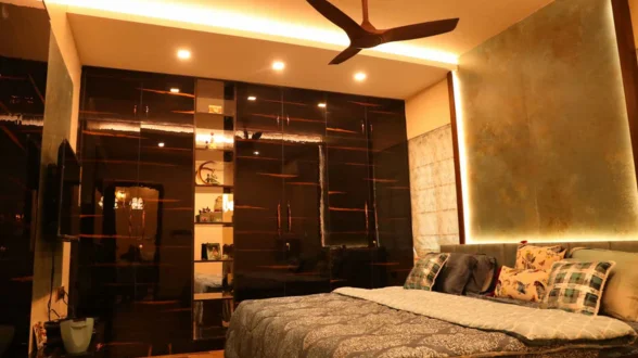 A warm and inviting bedroom featuring a soft bed, a ceiling fan, and a hanging mirror with lights.