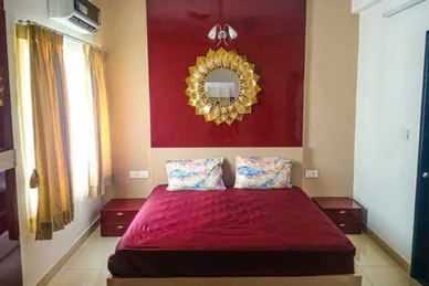 A bedroom with bright red walls and a beautiful gold mirror gives a warm setting with stylish decor.