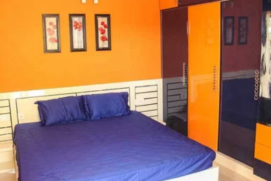 A bedroom with bright orange walls & a trendy blue bed offers the best interior design services.