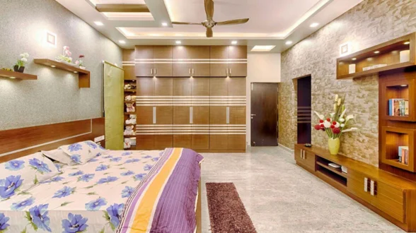 A large, comfortable bedroom with a bed, dresser, fake ceiling, and contemporary wardrobe.