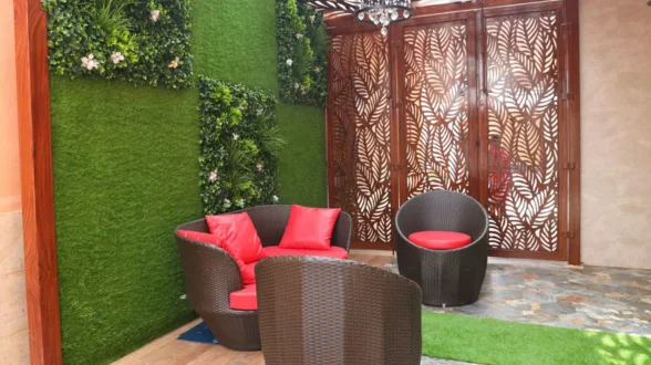 A wall full of lush plants and fake grass in the living room offers a natural & reviving ambiance.