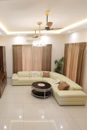 A living room with a soft sofa white furnishings and a ceiling fan gives a stunning look.