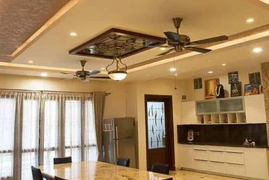 An intricately designed ceiling with fan and kitchen, this spacious dining showcases its features.