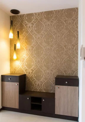 A room featuring a wallpapered wall and an elegant wooden cabinet with a beautiful hanging light.