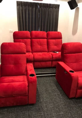 The private film industry room has comfortable home theater sofas and red tables and chairs.