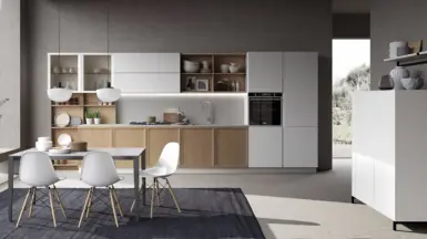 A contemporary kitchen featuring white cabinets with warm wooden floors & arranged with dining table