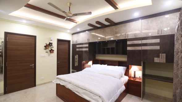 A nice bedroom with a comfy bed, high-end wardrobes, and a ceiling fan that provides a cool breeze.
